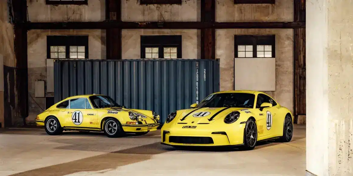 Porsche 911 2.5 S/T von 1972 und moderner Porsche 911 S/T, beide in Hellgelb und Startnummer 41, stehen nebeneinander in einer Halle.