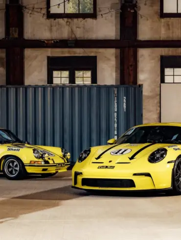 Porsche 911 2.5 S/T von 1972 und moderner Porsche 911 S/T, beide in Hellgelb und Startnummer 41, stehen nebeneinander in einer Halle.