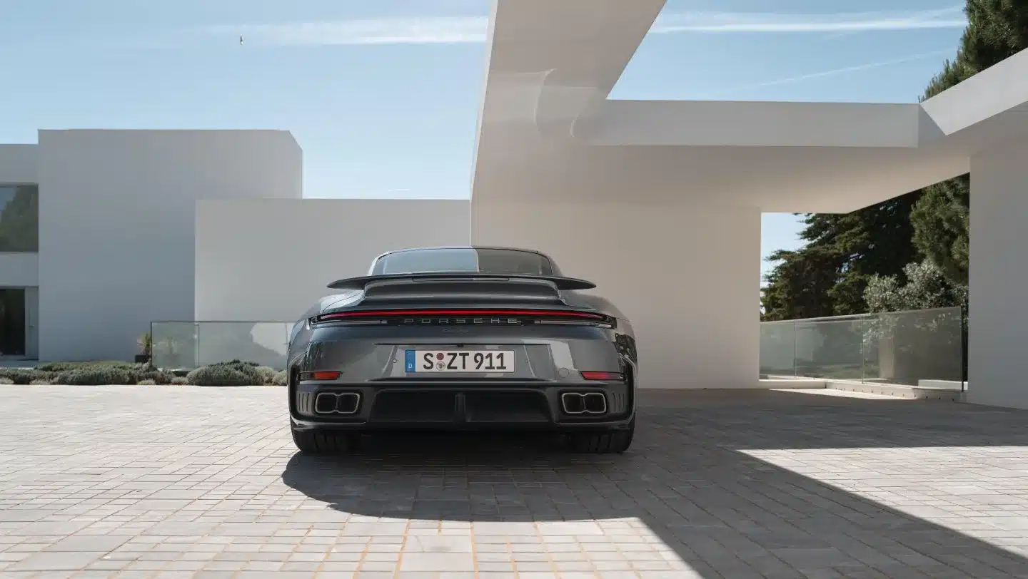 Heckansicht eines Porsche 911 Turbo S, geparkt vor einem modernen weißen Gebäude mit klarer Architektur