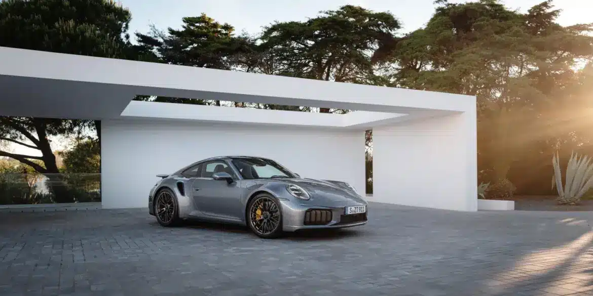 Porsche 911 Turbo S Performance-Hybrid 2025 in Silber vor moderner Garage bei Sonnenuntergang