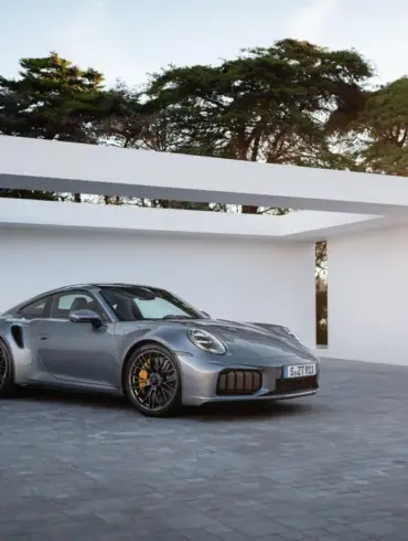 Porsche 911 Turbo S Performance-Hybrid 2025 in Silber vor moderner Garage bei Sonnenuntergang