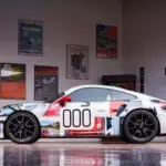 Seitenansicht eines Porsche 911 Turbo S Lightweight 2022 mit auffälligem Motorsport-Design in einer stilvollen Garage.