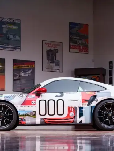 Seitenansicht eines Porsche 911 Turbo S Lightweight 2022 mit auffälligem Motorsport-Design in einer stilvollen Garage.