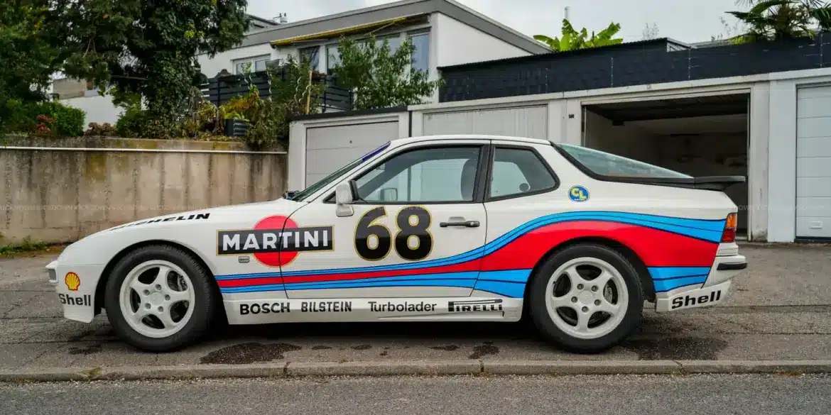 Porsche 944 von 1986, weiß mit Martini-Racing-Folierung, seitlich fotografiert vor Garagen