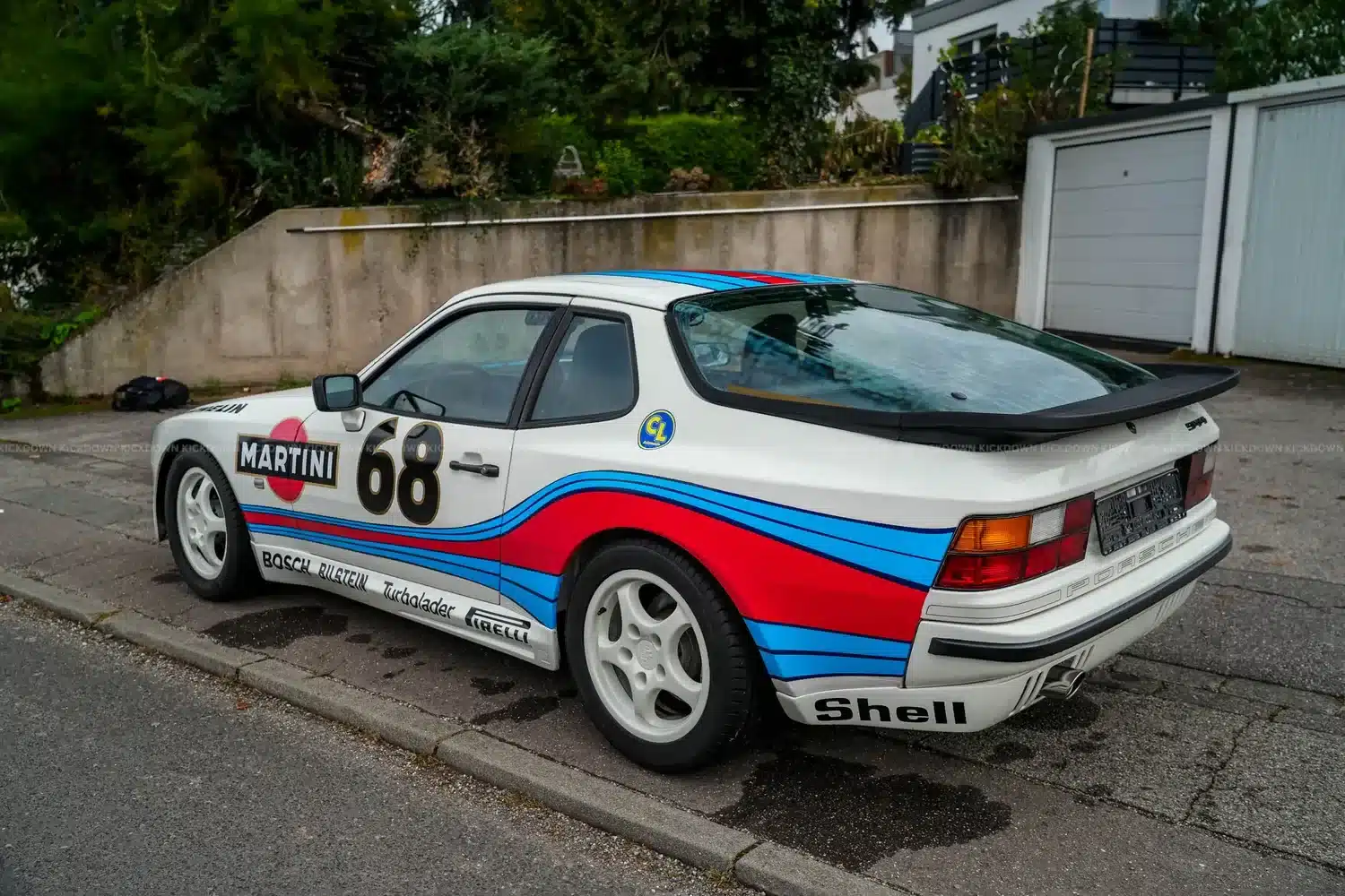Porsche 944 aus 1986 in Weiß mit Martini-Racing-Folierung und Startnummer 68, seitliche Ansicht, geparkt am Straßenrand