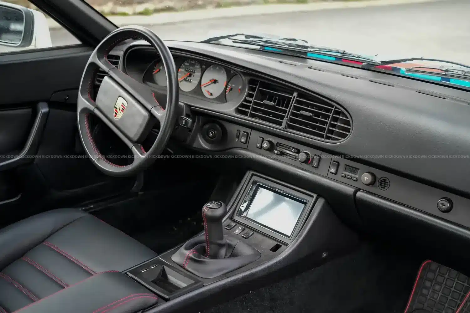 Schwarzer Lederausstattung und Armaturenbrett eines Porsche 944 Baujahr 1986 mit roten Ziernähten