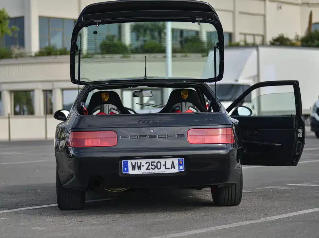 Porsche 968 Club Sport von hinten, Kofferraumdeckel und Tür geöffnet, Parkplatzsituation.