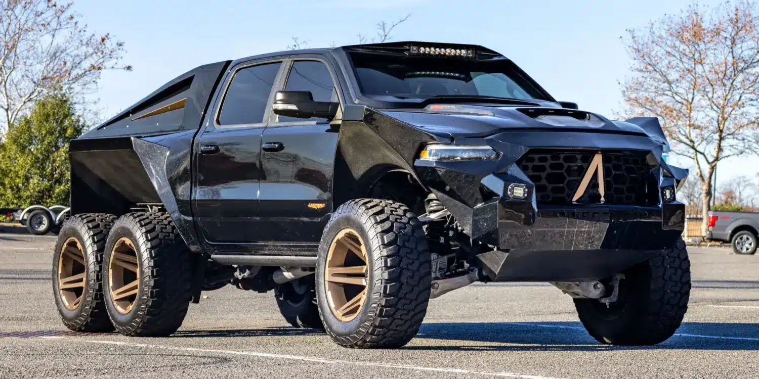 Apocalypse Juggernaut 6x6 Pickup, schwarz, mit sechs großen Offroad-Rädern, breiten Kotflügeln und massiver Front im Freien stehend.