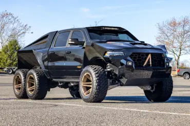 Apocalypse Juggernaut 6x6 Pickup, schwarz, mit sechs großen Offroad-Rädern, breiten Kotflügeln und massiver Front im Freien stehend.
