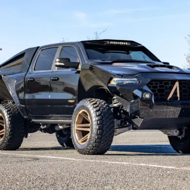 Apocalypse Juggernaut 6x6 Pickup, schwarz, mit sechs großen Offroad-Rädern, breiten Kotflügeln und massiver Front im Freien stehend.