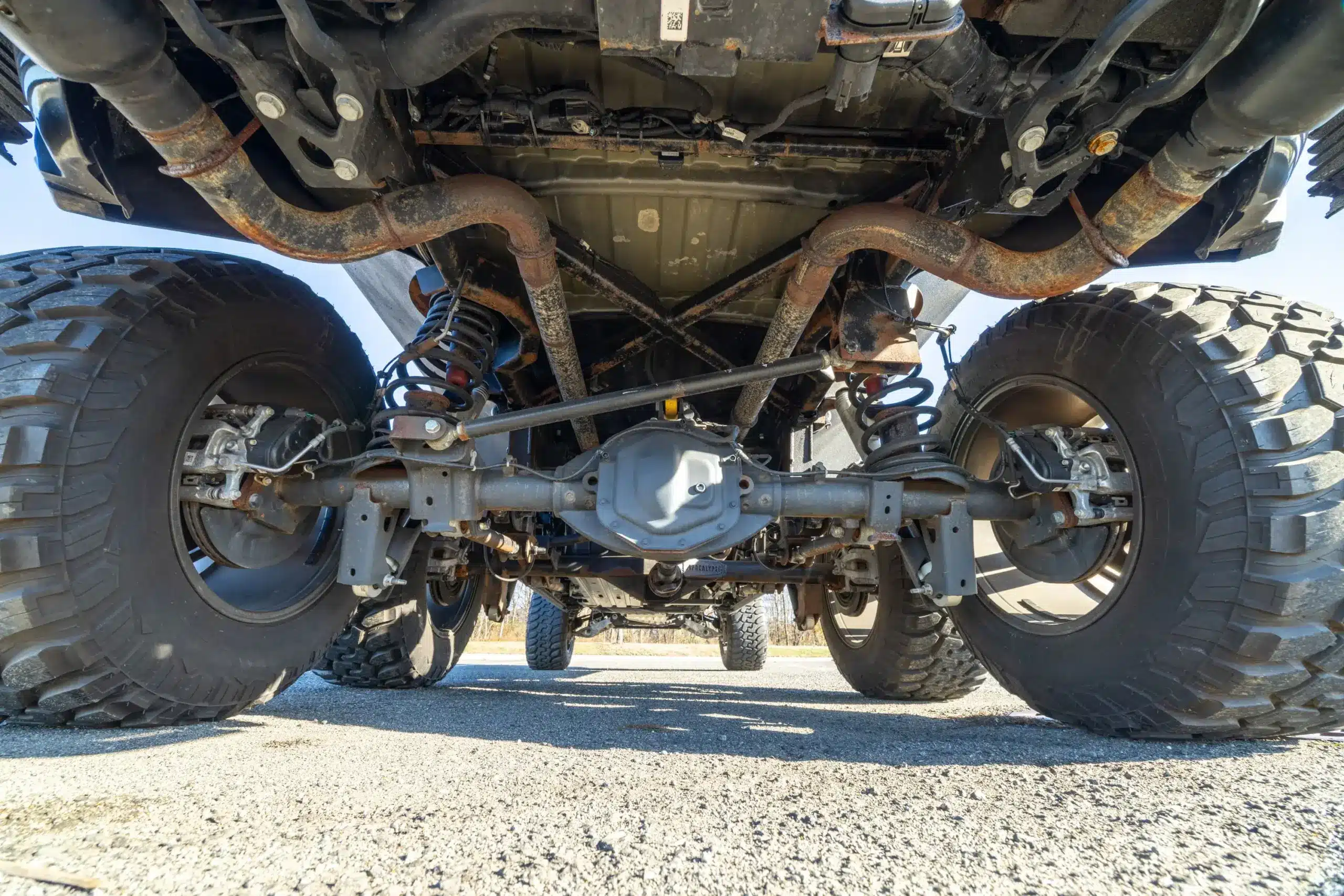 Unterbodenaufnahme mit Fokus auf die Sechsrad-Antriebsachse und die robuste Offroad-Federung des Apocalypse Juggernaut 6x6.