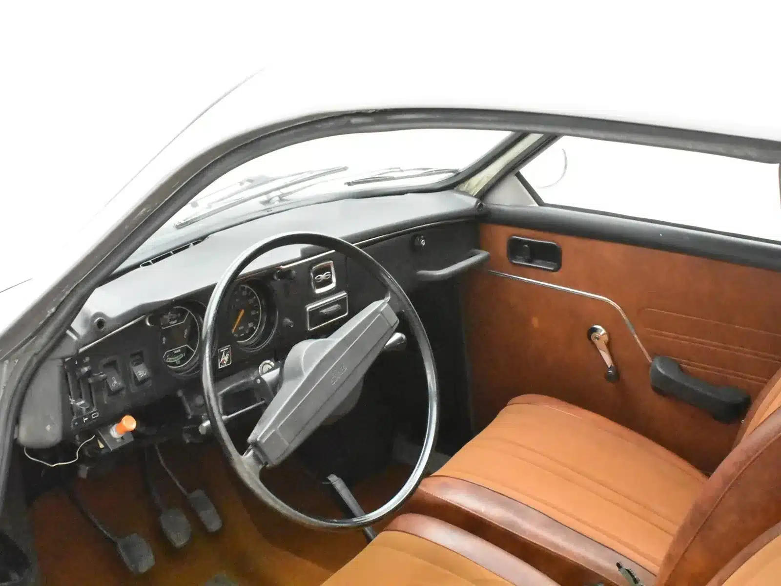 Innenraum und Armaturenbrett eines Saab 96 Baujahr 1975 mit brauner Innenausstattung und Lenkradansicht.