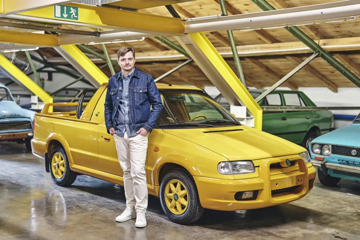 Original Skoda Felicia Fun in Gelb mit einem Mann stehend daneben im Ausstellungsraum.