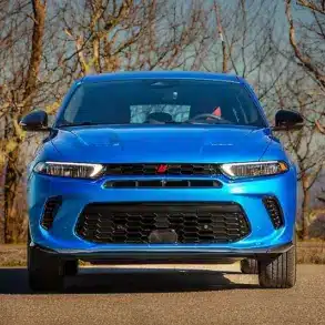 Frontansicht eines blauen Dodge SUV auf einer Straße mit kahlen Bäumen im Hintergrund