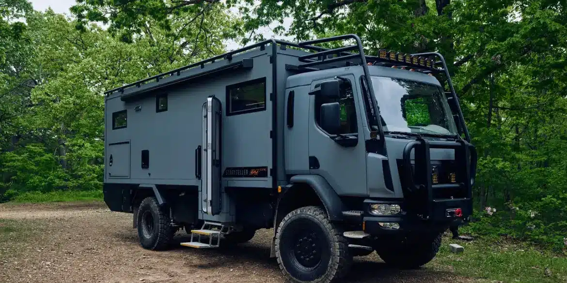 Storyteller Overland GXV EPIC Expeditionsmobil geparkt im Wald auf unbefestigtem Untergrund.