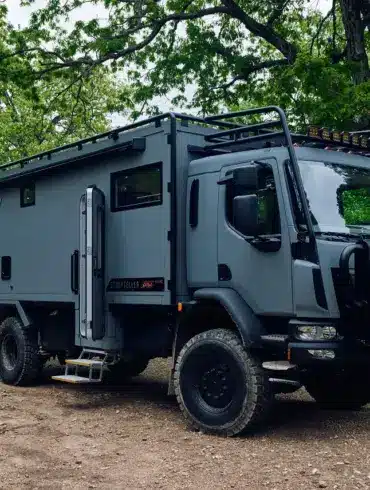 Storyteller Overland GXV EPIC Expeditionsmobil geparkt im Wald auf unbefestigtem Untergrund.