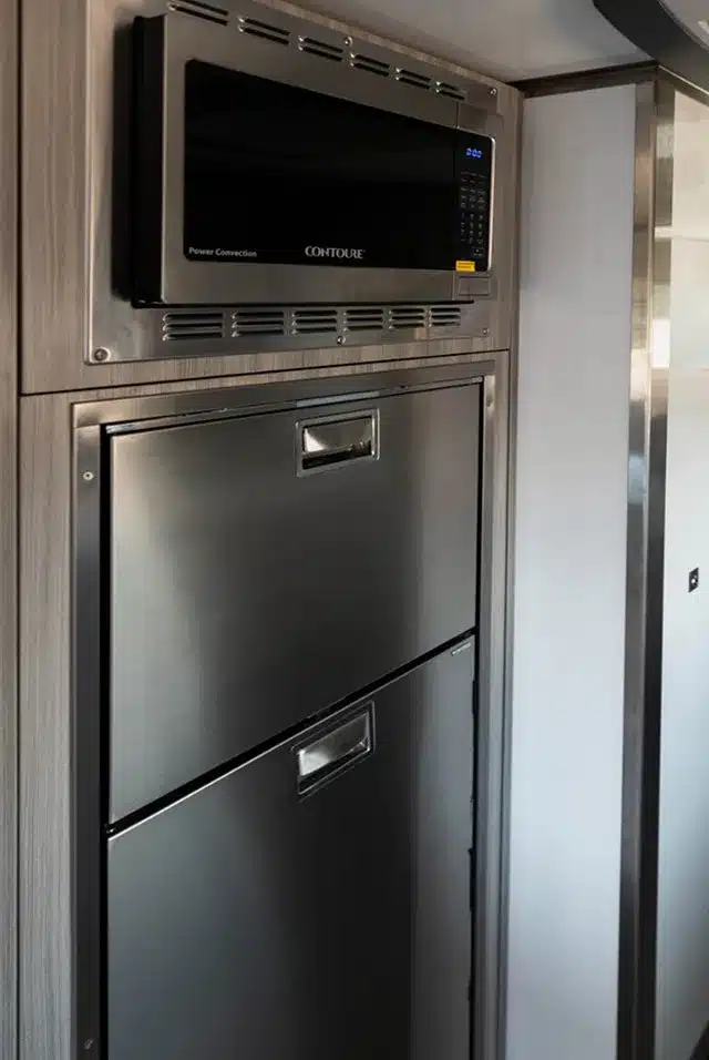 Integrierte Mikrowelle und Edelstahl-Kühlschrank in der Küche des Storyteller Overland GXV EPIC Expeditionsmobils