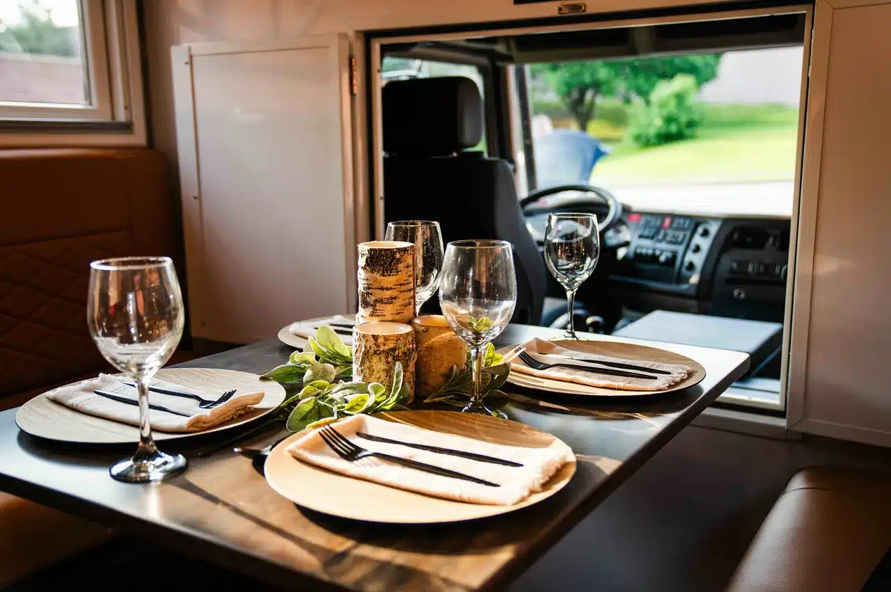 Innenraum des Storyteller Overland GXV EPIC mit gedecktem Esstisch und Sicht auf das Fahrerhaus