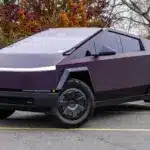 Tesla Cybertruck 2024 in violetter Lackierung, geparkt auf einem Außenparkplatz, markantes kantiges Design.