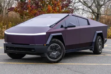 Tesla Cybertruck 2024 in violetter Lackierung, geparkt auf einem Außenparkplatz, markantes kantiges Design.