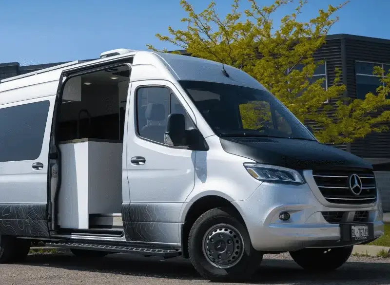 Vollausgebauter Kastenwagen Vancini Georgian Bay auf Basis eines silbernen Mercedes Sprinter 3500 Dually mit offener Seitentür und Outdoor-Folierung.