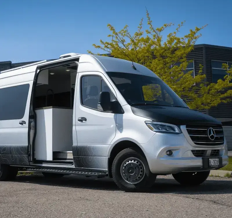 Vollausgebauter Kastenwagen Vancini Georgian Bay auf Basis eines silbernen Mercedes Sprinter 3500 Dually mit offener Seitentür und Outdoor-Folierung.
