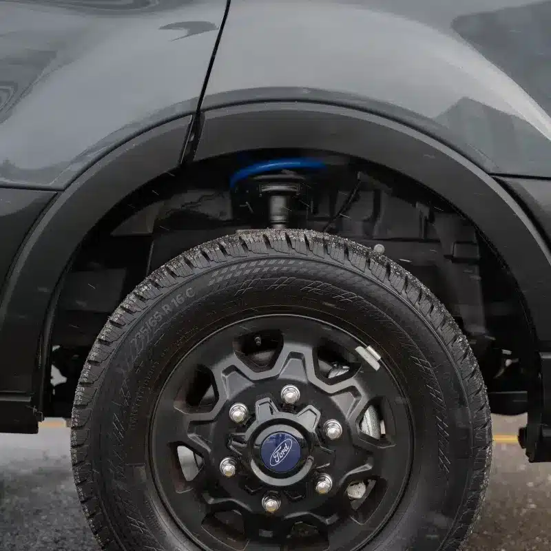 Nahaufnahme eines Ford Transit Rades mit Allrad-Aufhängung und Geländeprofil beim Camper Vancini Quetico.