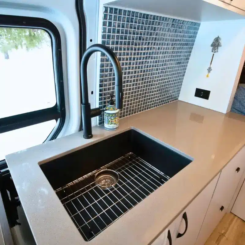 Küchenzeile mit Caesarstone-Quarzarbeitsplatte und mattschwarzem Spülbecken im ausgebauten Mercedes Sprinter Killarney
