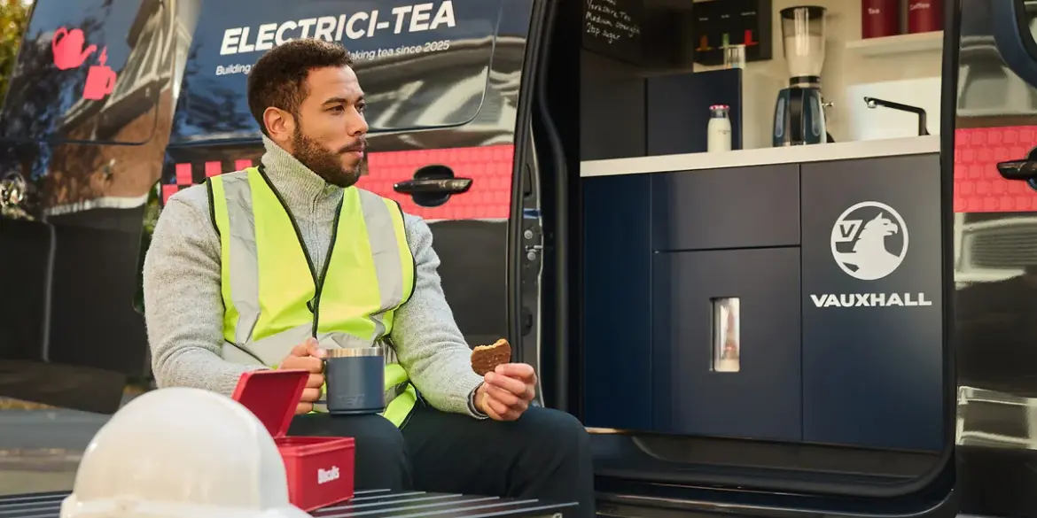Handwerker genießt Tee und Keks vor einem Vauxhall Vivaro Electrici-TEA mit integrierter Teeküche.