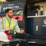 Handwerker genießt Tee und Keks vor einem Vauxhall Vivaro Electrici-TEA mit integrierter Teeküche.