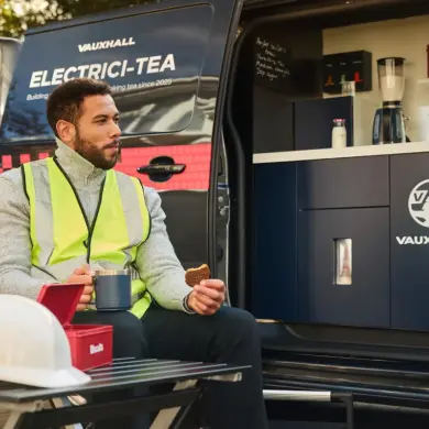 Handwerker genießt Tee und Keks vor einem Vauxhall Vivaro Electrici-TEA mit integrierter Teeküche.