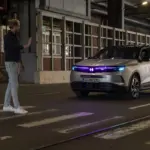 Vauxhall Grandland mit cyanfarbener Lichtsignatur hält an einem Zebrastreifen vor einem Fußgänger