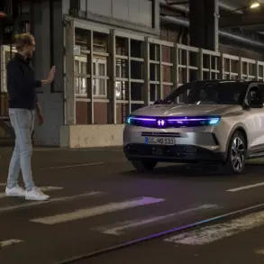 Vauxhall Grandland mit cyanfarbener Lichtsignatur hält an einem Zebrastreifen vor einem Fußgänger