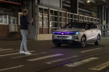 Vauxhall Grandland mit cyanfarbener Lichtsignatur hält an einem Zebrastreifen vor einem Fußgänger
