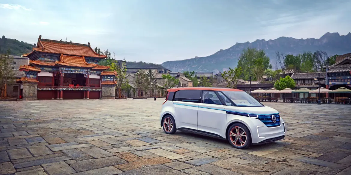 Der elektrische Volkswagen BUDD-e steht auf einem weiten Steinplatz vor einer chinesischen Tempelanlage und Bergen im Hintergrund.