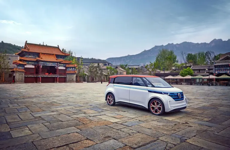 Der elektrische Volkswagen BUDD-e steht auf einem weiten Steinplatz vor einer chinesischen Tempelanlage und Bergen im Hintergrund.