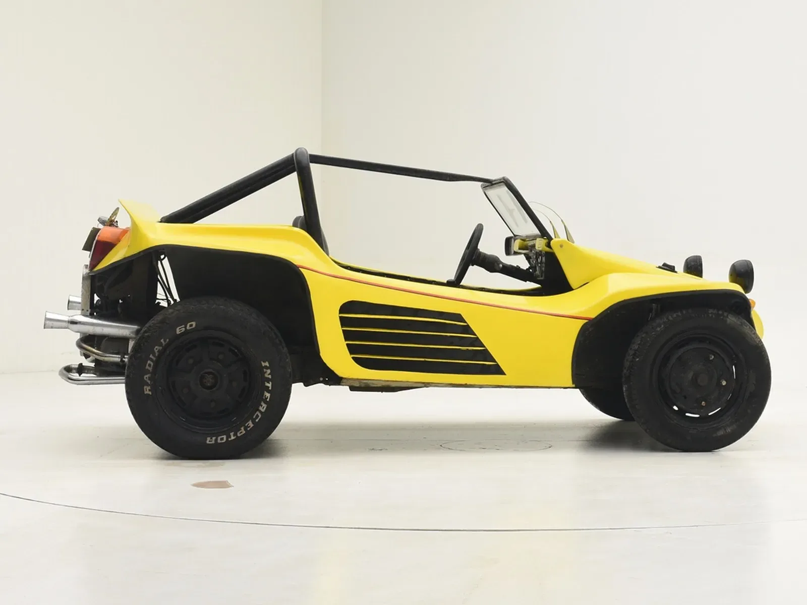 Gelber Volkswagen Buggy 1600, Baujahr 1962, seitlich fotografiert, mit sichtbarem Überrollbügel und minimalistischer Ausstattung