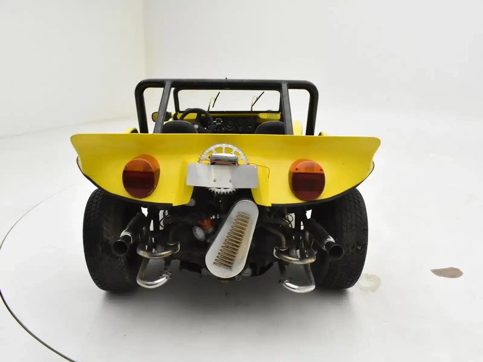 Rückansicht eines gelben Volkswagen Buggy 1600 von 1962, mit sichtbarem Motor und markantem Leichtbau-Design.