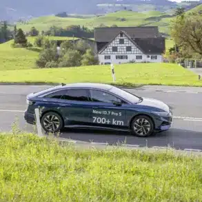 Volkswagen ID.7 Pro S fährt auf einer Landstraße durch grüne Hügellandschaft, Schriftzug 700+ km auf dem Fahrzeug