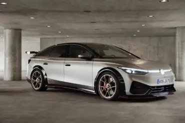 Seitliche Ansicht des Volkswagen ID.X Performance Elektro-Konzeptfahrzeugs in einer Tiefgarage mit markanten Sportfelgen und großem Heckflügel.