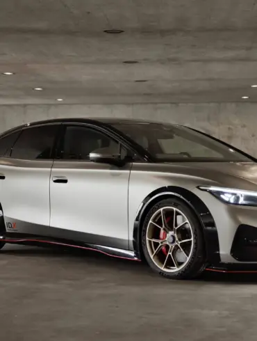 Seitliche Ansicht des Volkswagen ID.X Performance Elektro-Konzeptfahrzeugs in einer Tiefgarage mit markanten Sportfelgen und großem Heckflügel.