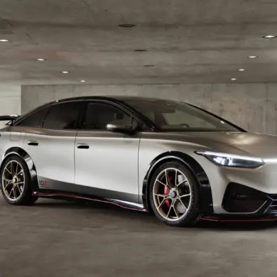 Seitliche Ansicht des Volkswagen ID.X Performance Elektro-Konzeptfahrzeugs in einer Tiefgarage mit markanten Sportfelgen und großem Heckflügel.