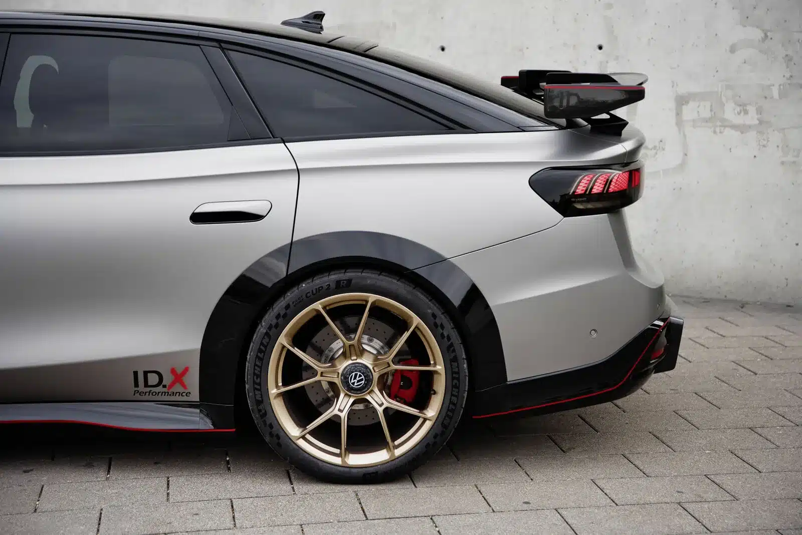 Heckansicht des Volkswagen ID.X Performance mit Carbon-Heckflügel und goldener 20-Zoll-Sportfelge.