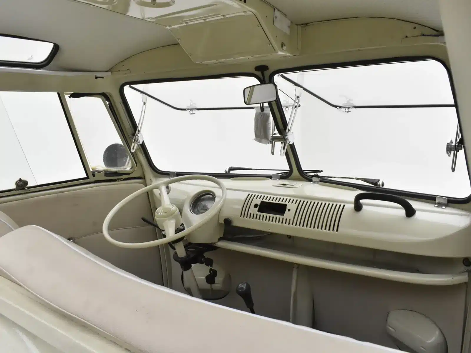 Innenraum und Cockpit eines Volkswagen T1 Samba Baujahr 1973 in hellem Beige mit Lenkrad, Armaturenbrett und geteilter Frontscheibe.