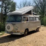 VW T2 Westfalia Camper von 1971 mit aufgeklapptem Dach, geparkt in einer natürlichen Umgebung