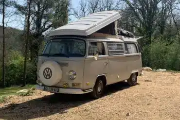 VW T2 Westfalia Camper von 1971 mit aufgeklapptem Dach, geparkt in einer natürlichen Umgebung