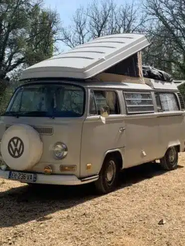 VW T2 Westfalia Camper von 1971 mit aufgeklapptem Dach, geparkt in einer natürlichen Umgebung