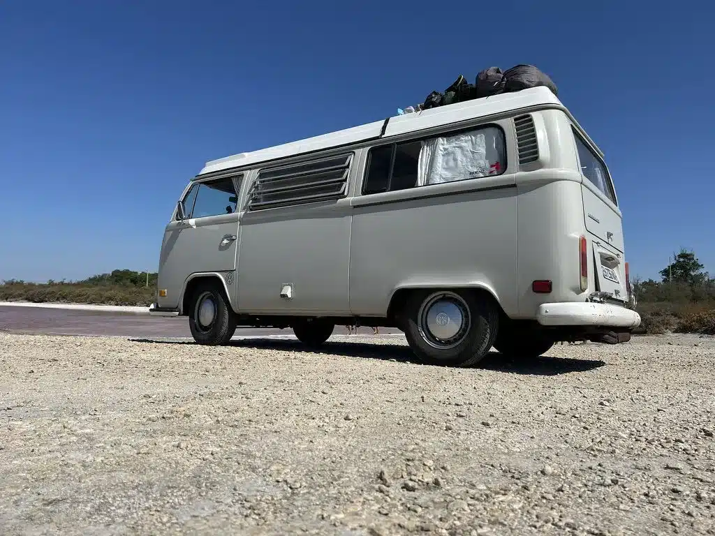 VW T2 Westfalia 1971 in mattem Satin-Grau, geparkt auf sandigem Untergrund mit Gepäck auf dem Klappdach.