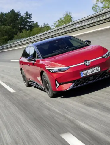 Roter VW ID.7 GTX fährt sportlich auf einer abgesperrten Teststrecke, aufgenommen von vorne seitlich.