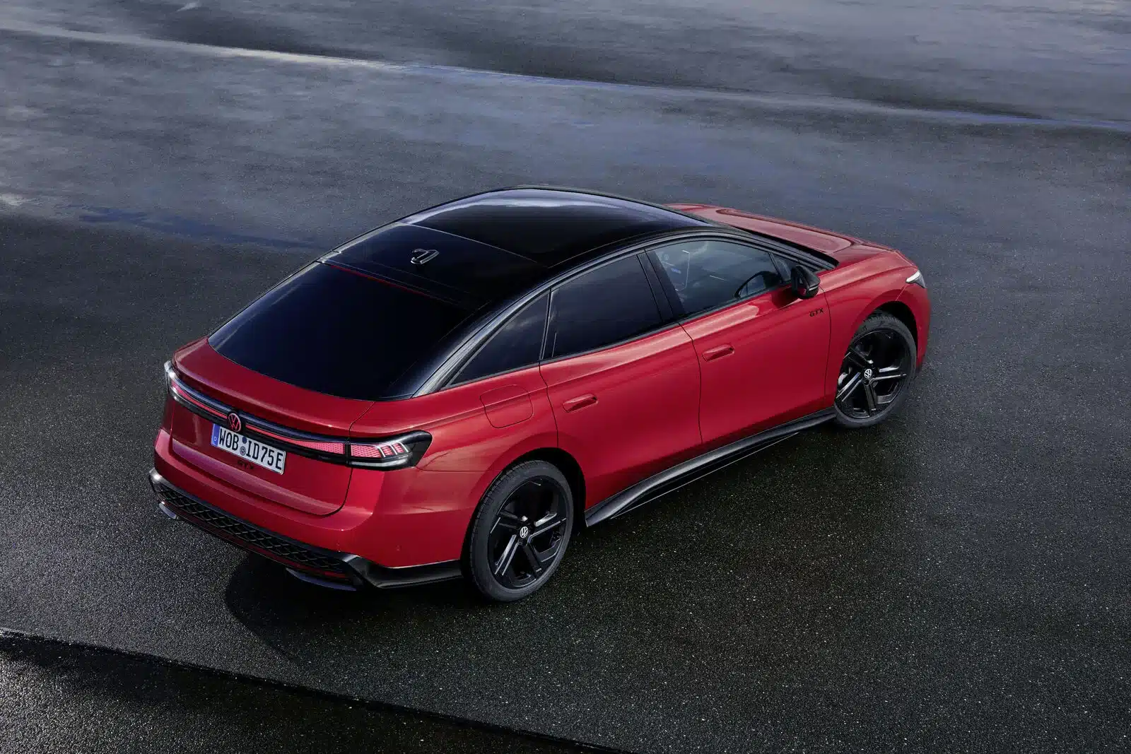 VW ID.7 GTX Heckansicht in Rot mit schwarzem Dach auf nassem Asphalt fotografiert.